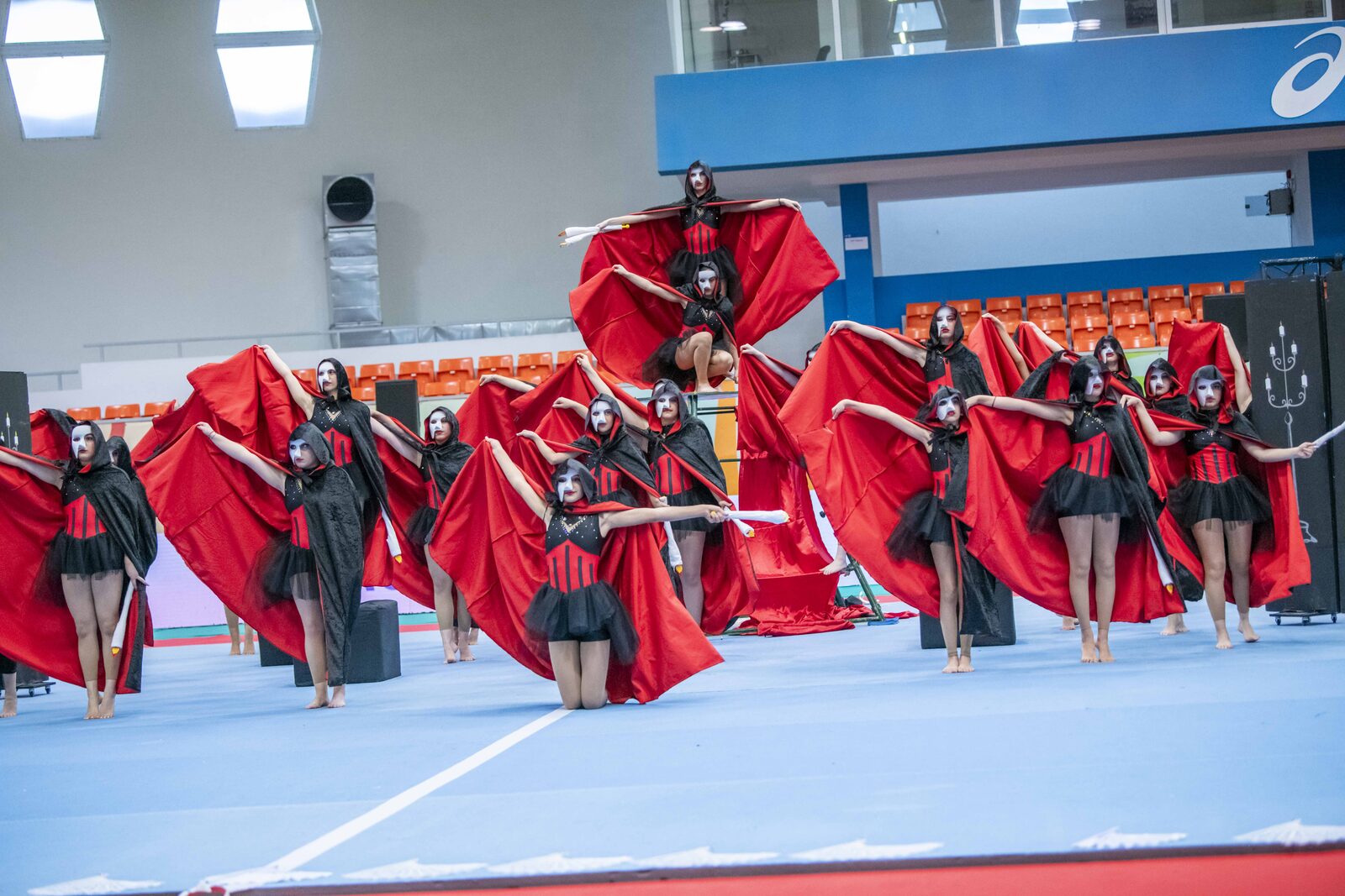 Ομαδική παρουσίαση Gymnastics for All με κόκκινα πανιά σε εσωτερικό γήπεδο