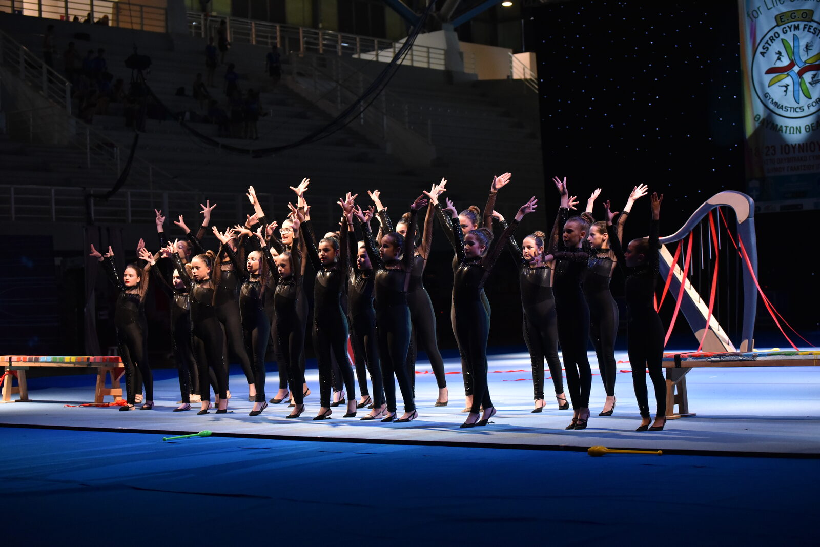 Ομαδική στιγμή σε σκηνική παρουσίαση Gymnastics for All με καλλιτεχνικό φωτισμό